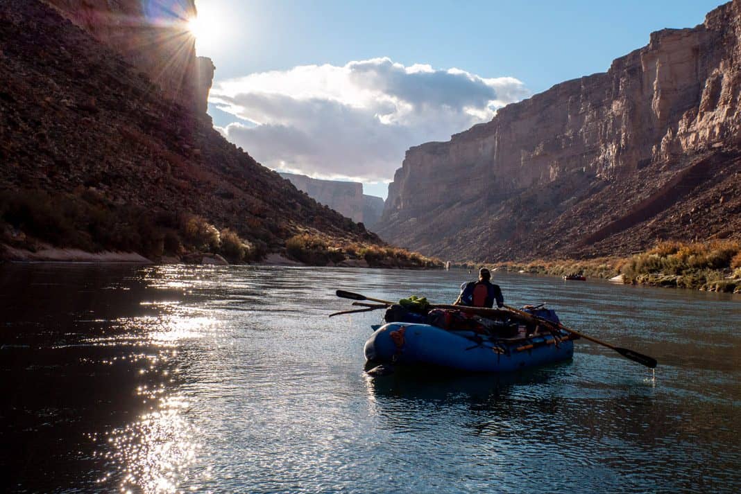 person paddling a raft down a scenic canyon