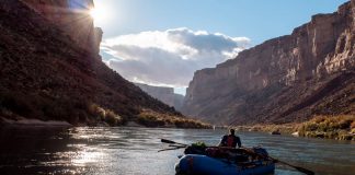 person paddling a raft down a scenic canyon