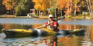 person paddling Wilderness Systems’ Tsunami 145 touring kayak on a lake