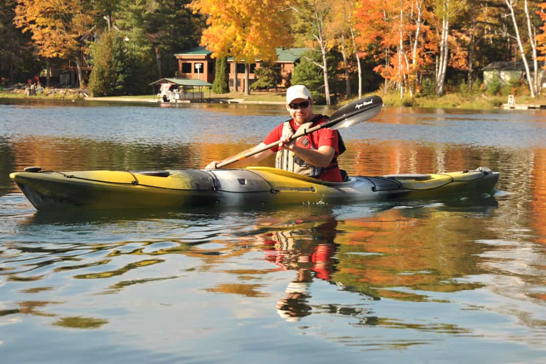 person paddling Wilderness Systems’ Tsunami 145 touring kayak on a lake