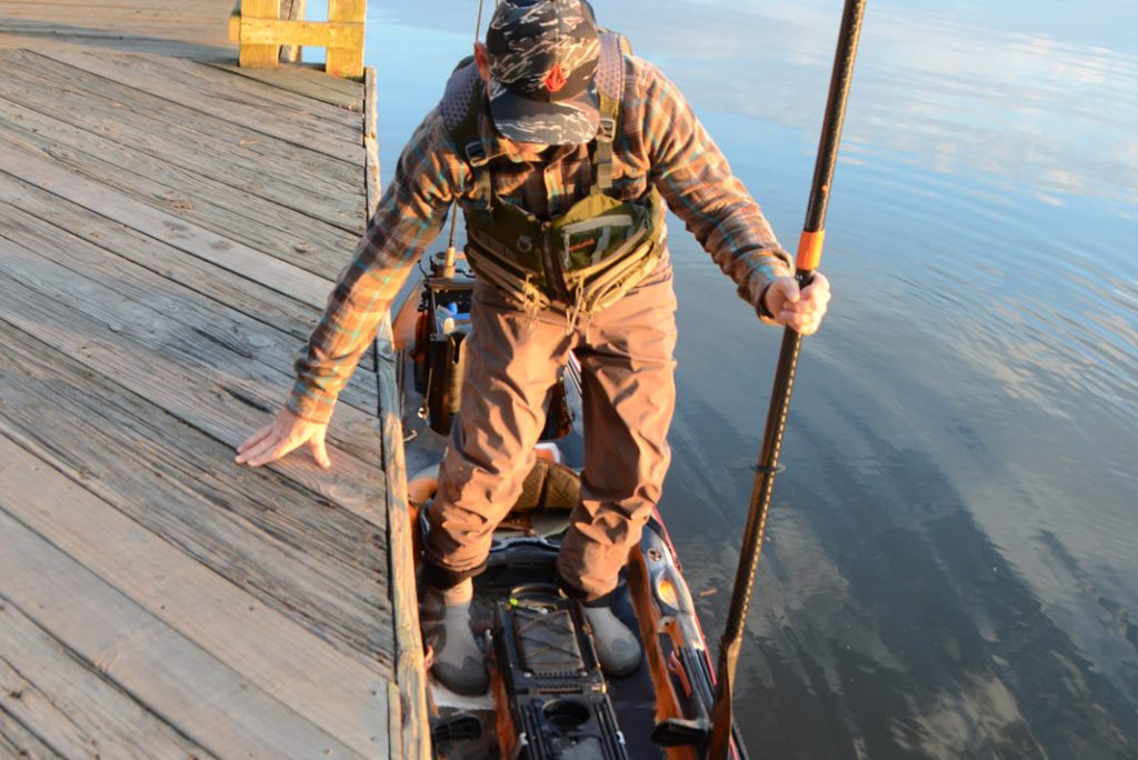 angler getting into his fishing kayak from the dock