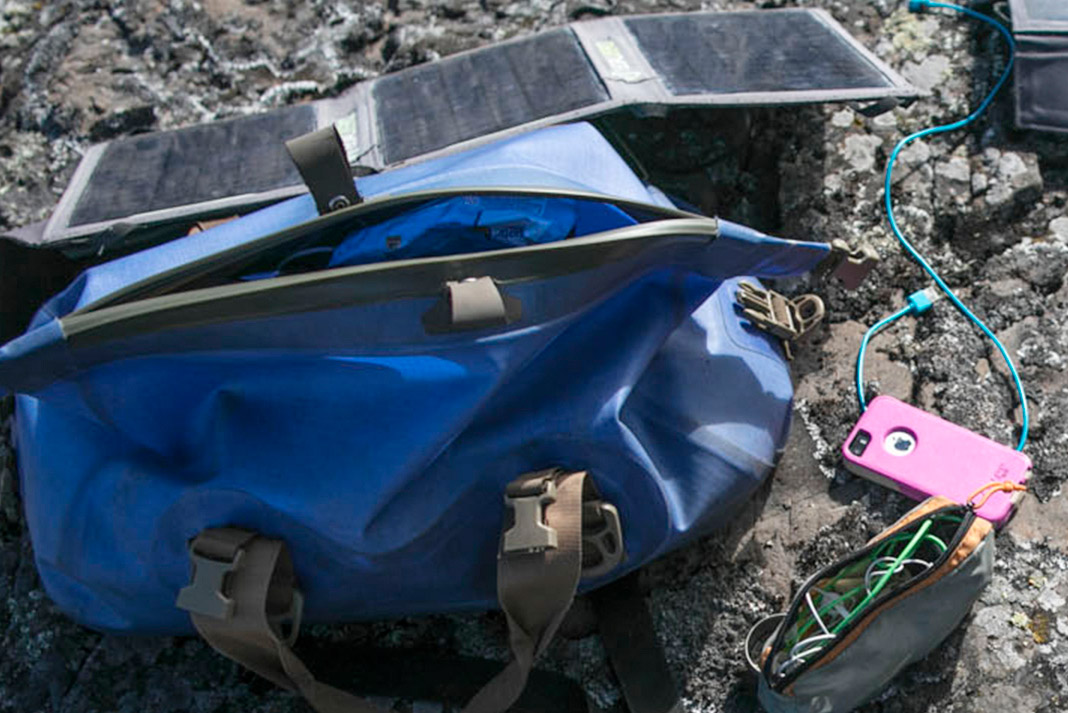 a cellphone and electronics sitting outside of a duffle bag