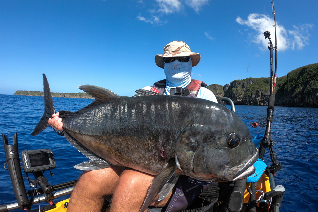 angler holds up giant trevally caught while kayak fishing in Guam