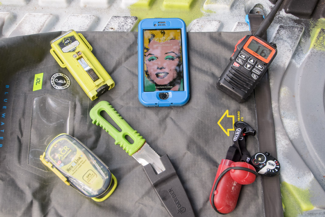 a selection of essential kayak safety equipment laid out on a deflated boat