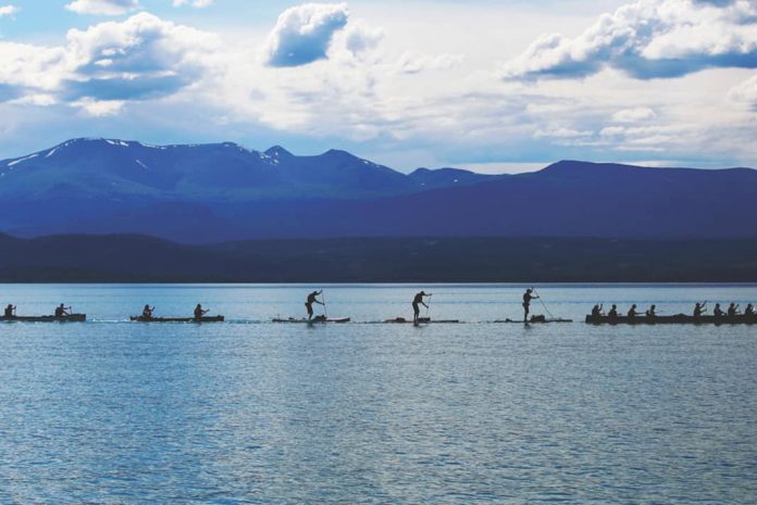 Paddlers in the midst of Yukon River Quest with beautiful mountains all around