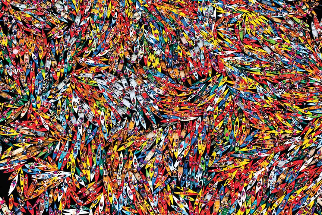 An overhead shot of many canoes and kayaks bunched together on the water.