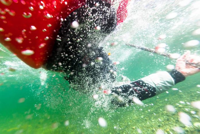 kayaker underwater while rolling a kayak