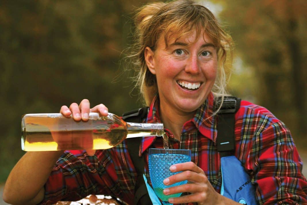 Virginia Marshall smiling while pouring wine into a cup wearing her paddling gear