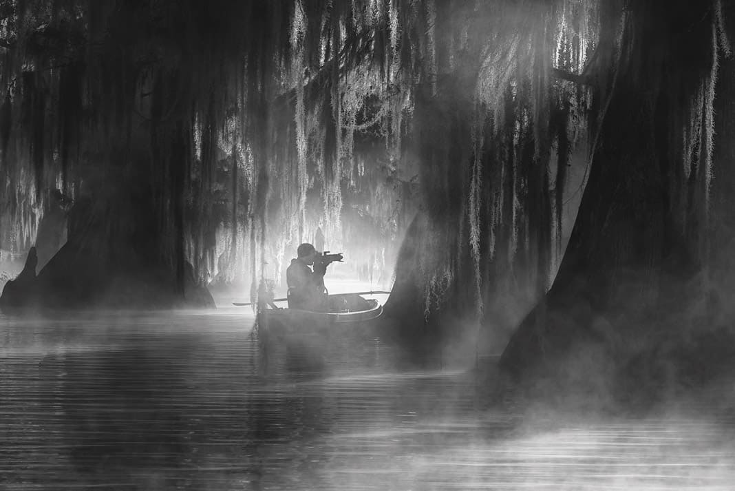 a man on his kayak photographing a swamp in Louisiana's Atchafalaya Basin
