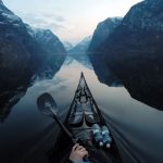 4 Secrets To Photographing Amazing Bow Shots a scenic view of mountains with the bow of a kayak and kayak paddles