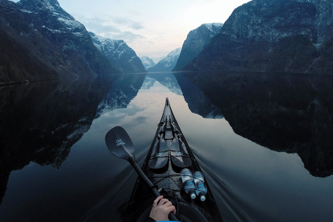 a scenic view of mountains with the bow of a kayak and kayak paddles