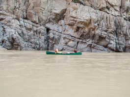 two men paddling a canoe on calm waters of the Grand Canyon