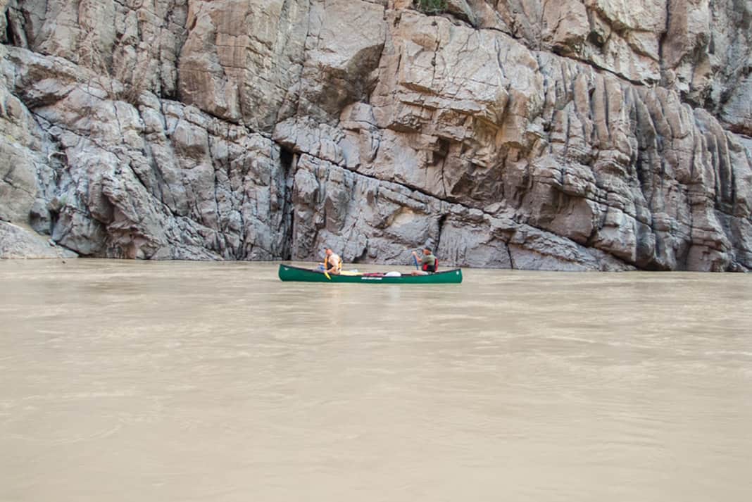 two men paddling a canoe on calm waters of the Grand Canyon
