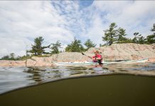 Person kayaking along a rocky shoreline