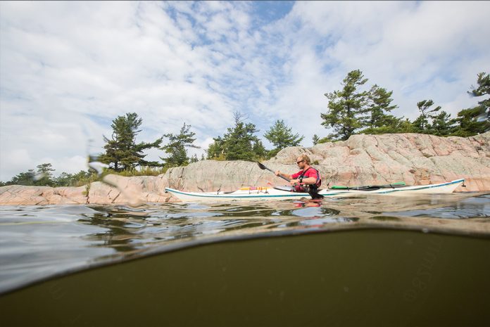 Person kayaking along a rocky shoreline