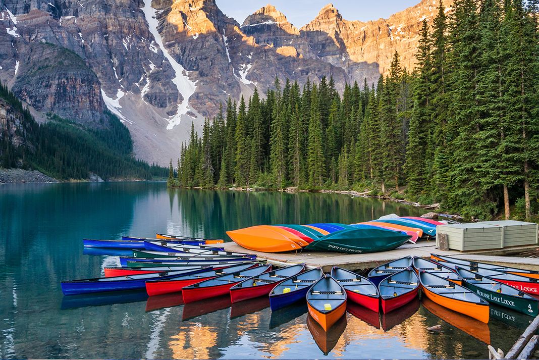 Canoes tied off at dock with mountains in background