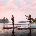 The Ultimate Guide To Buying A Used Paddleboard Two women paddling paddleboards on a lake