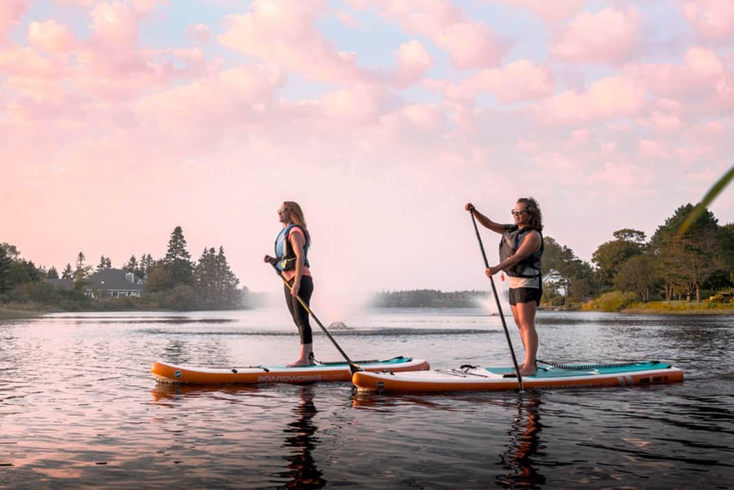 Two women paddling paddleboards on a lake