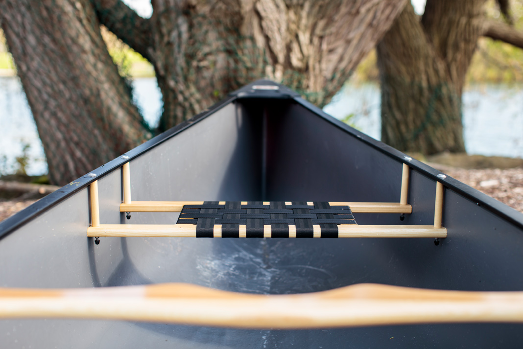 Photo of the bow of a plastic canoe on land.