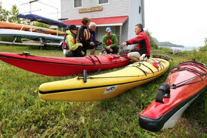 People sitting on grass beside kayaks