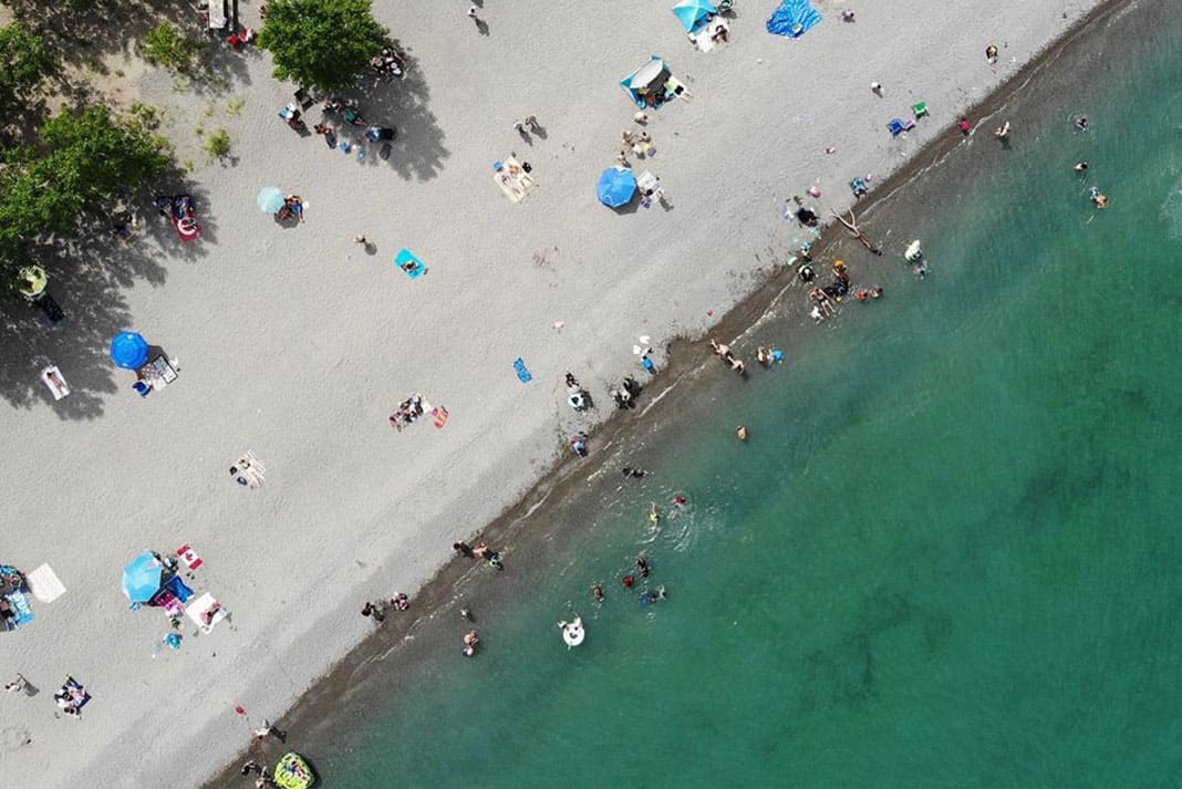 Overhead shot of beach with umbrellas and people walking on it