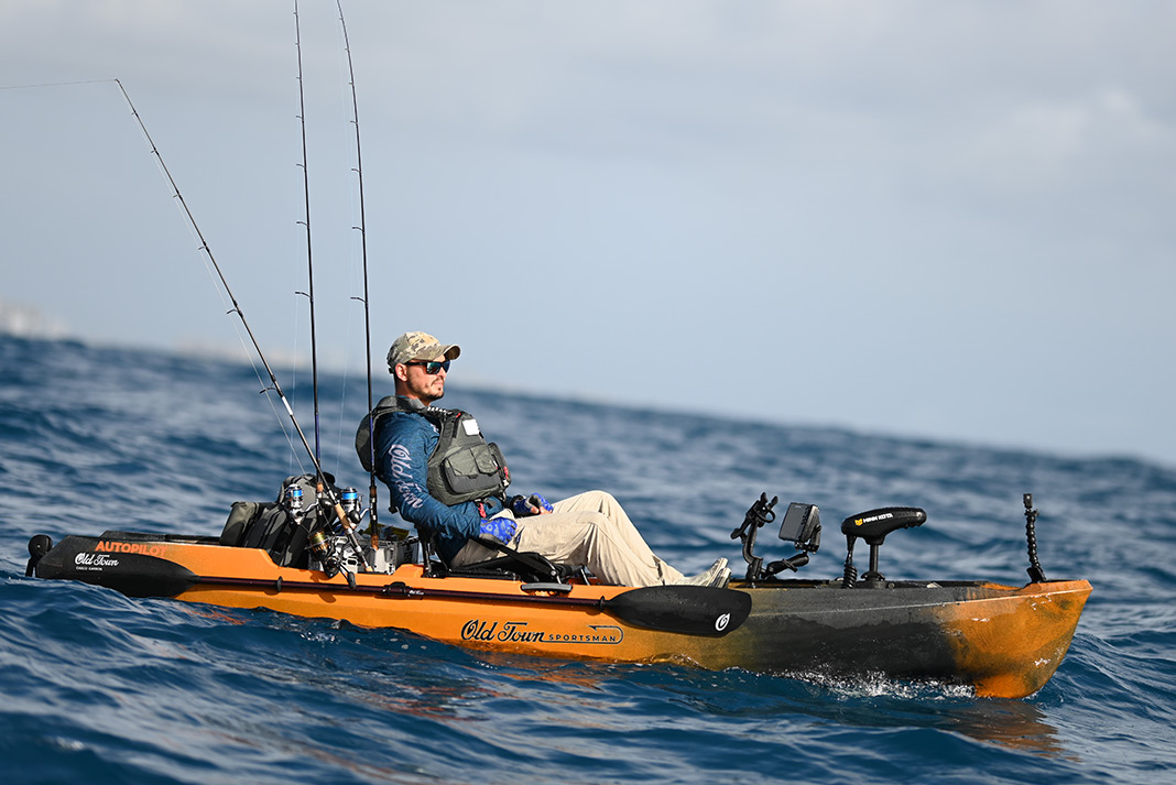 Man riding out the waves in a fishing kayak.