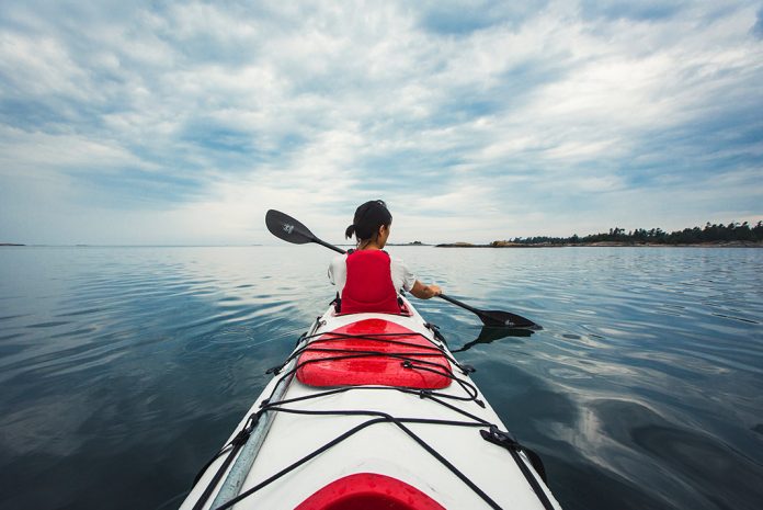 Shot from back of a kayak of a woman paddling