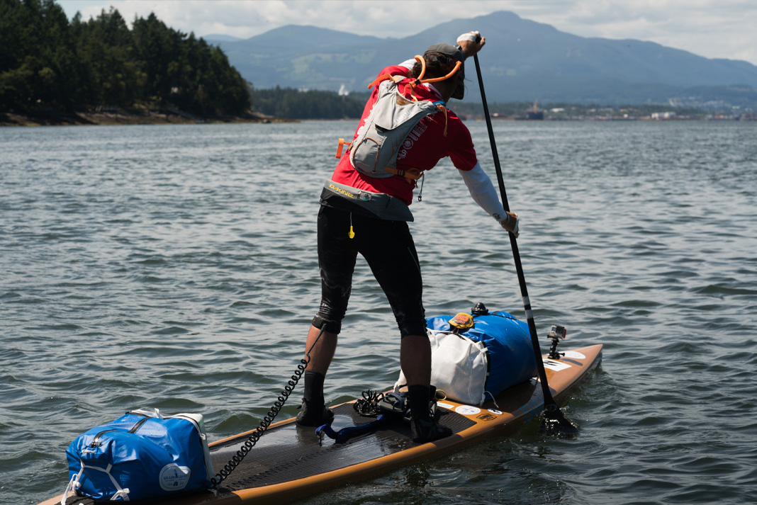 Man on paddleboard with gear strapped down