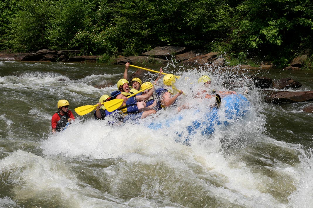 Group of people in a raft going off a wave