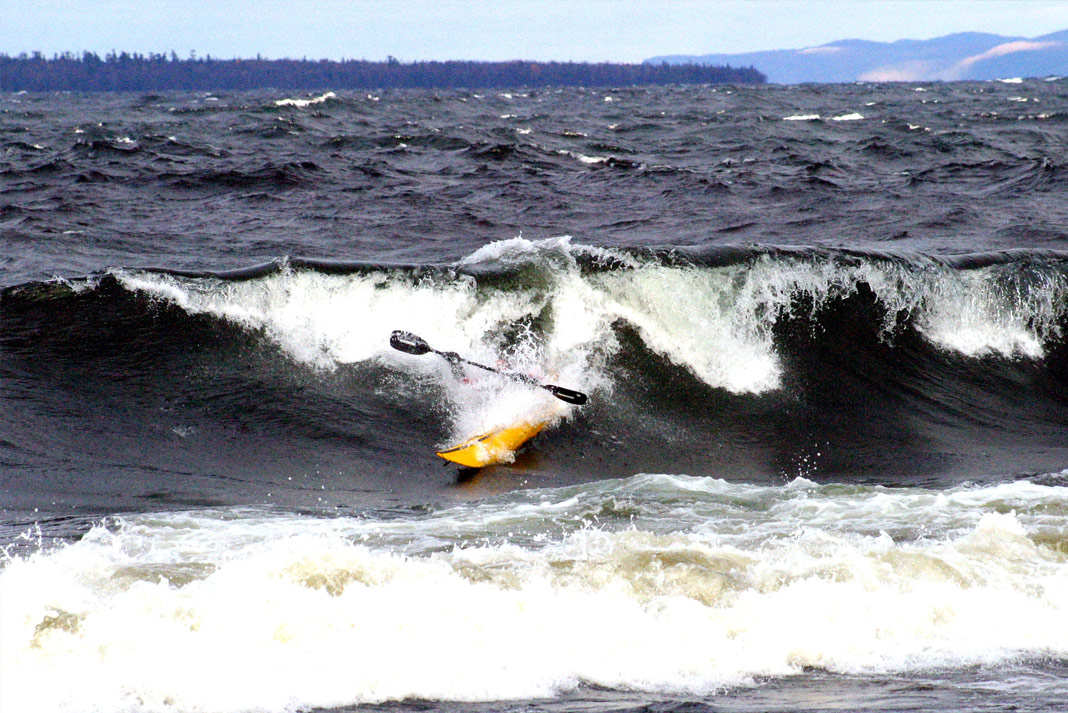 Person in yellow sea kayak coming off a wave