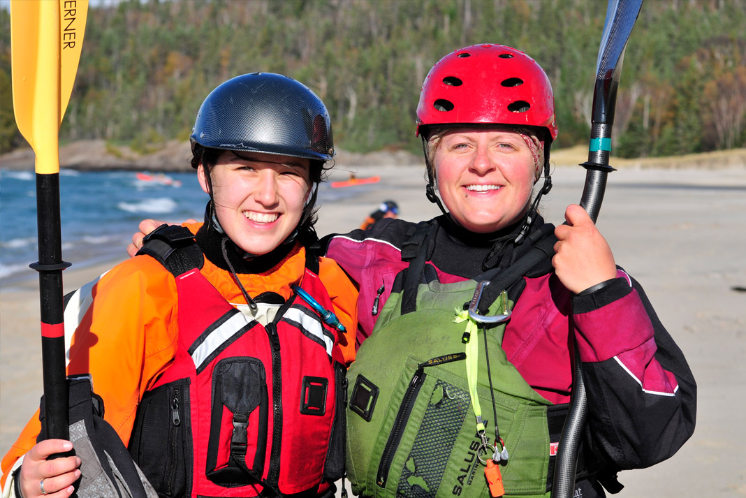Two women wearing paddling gear, arm in arm