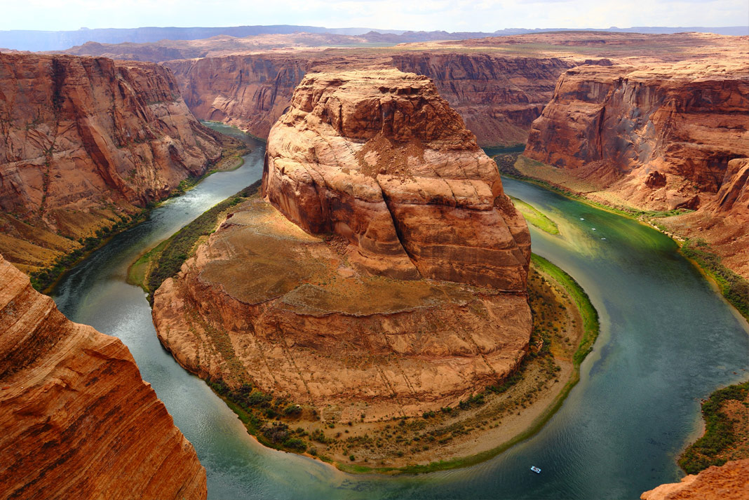 River wraps around a rock formation in the Grand Canyon