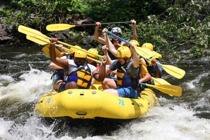 People in yellow raft raising their paddles in the air