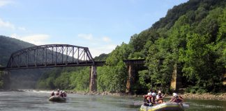 Two rafts on river with rail bridge in background