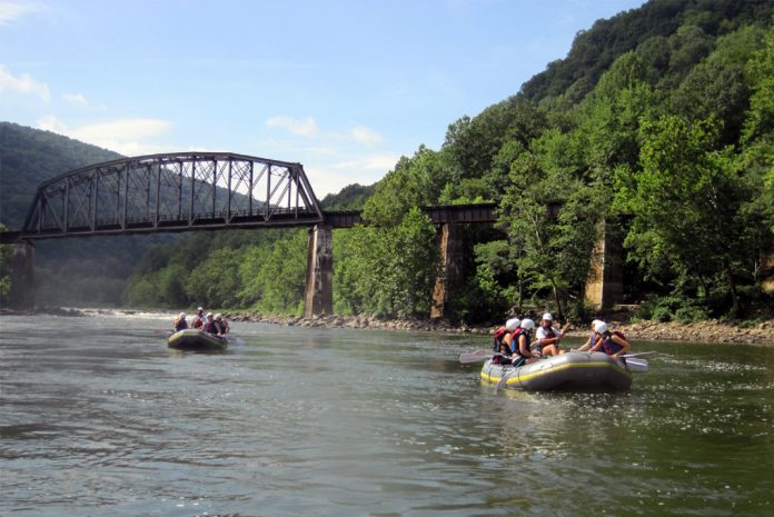Two rafts on river with rail bridge in background