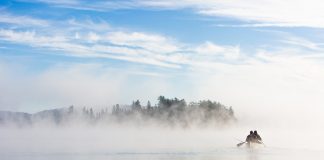 Two people paddling a canoe on a misty lake