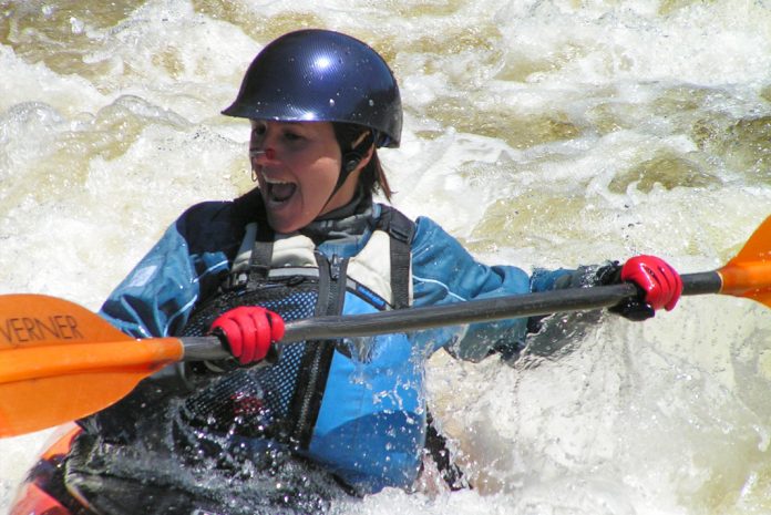 Woman holding into a kayak paddle, wearing red gloves