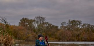 Woman solo paddling canoe with double blade paddle