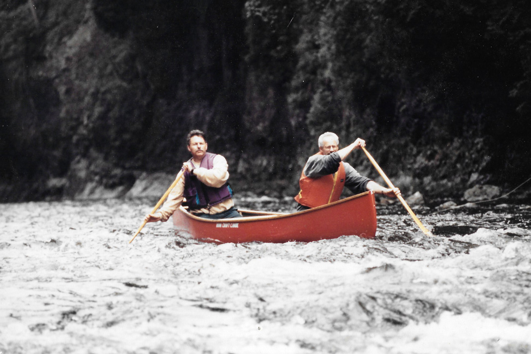 Two men paddling a red Nova Craft canoe