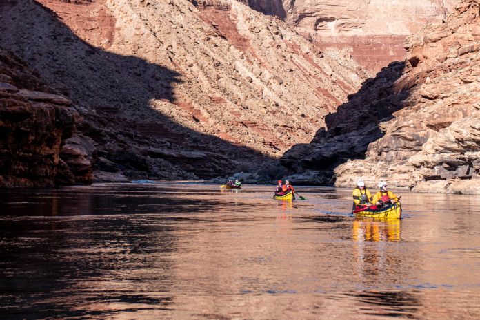 Canoes on river with canyon walls on either side
