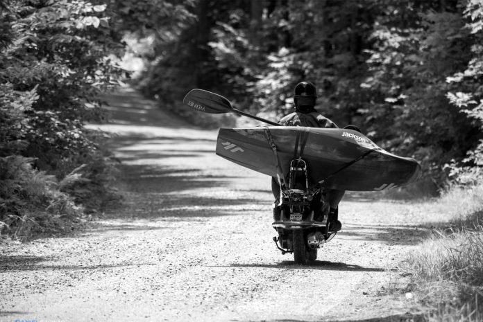 Person on a moped with kayak strapped to the back