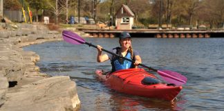 A woman paddles along the shore in a Pakayak Bluefin 14 packable kayak