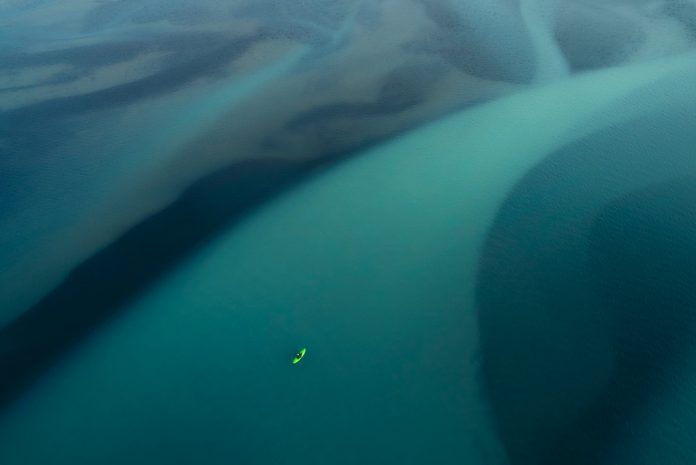 Photograph of a kayaker paddling glacier runoff.
