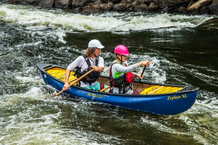 A father and son paddle a blue Esquif Zephyr 2.0 XL whitewater canoe.
