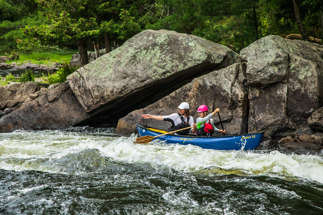 A father and son paddle a blue whitewater canoe.