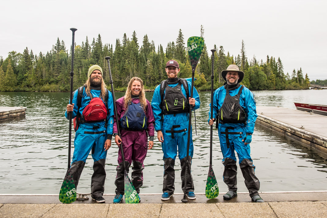 A group of paddleboarders pose in their gear and the boat launch.