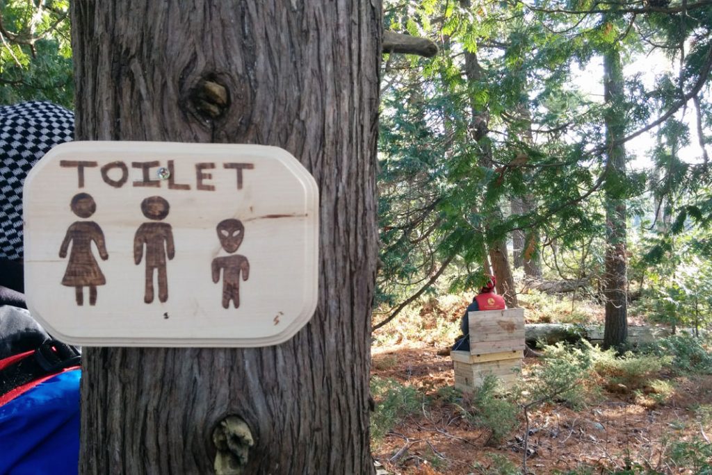 A person uses a backcountry toilet
