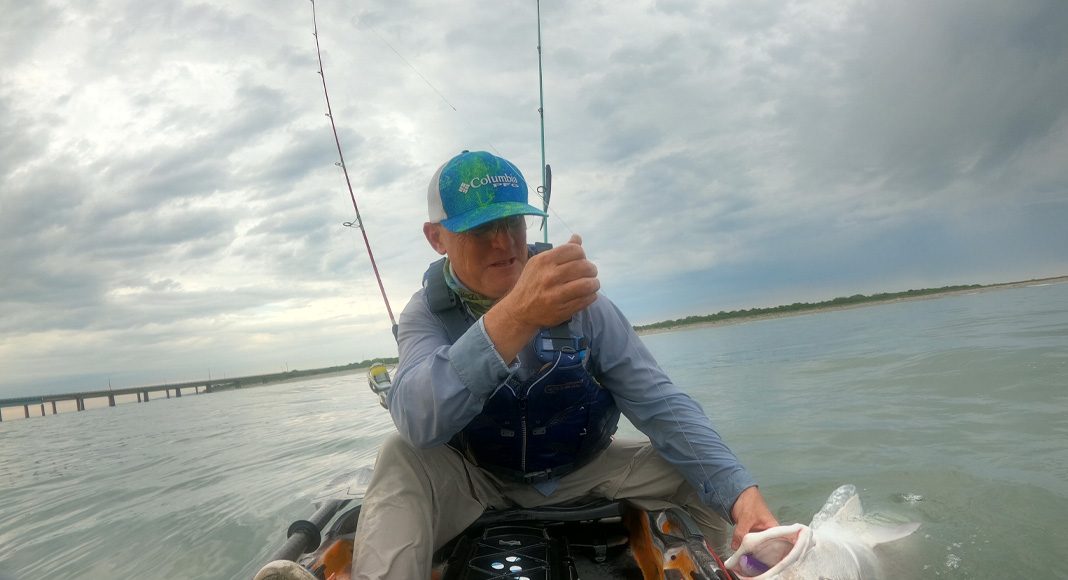 A kayak angler demonstrates the proper technique for landing a fish in a kayak