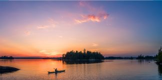 A kayaker paddles towards and island at sunset
