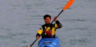 Man in kayak demonstrates high angle paddling style